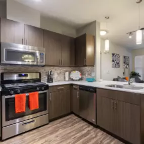 Kitchen with Quartz Countertops, Stainless Appliances and Wood-Inspired Flooring.