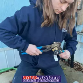 A Roto-Rooter technician is focused on adjusting a plumbing valve using channel-lock pliers, highlighting hands-on expertise in residential plumbing services.