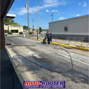 Two Roto-Rooter technicians are operating equipment to service or clean drainage lines in a McDonald’s drive-thru area, showcasing their commercial plumbing expertise.