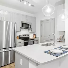 A modern kitchen with a stainless steel refrigerator and white countertops.
