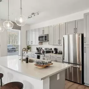 A modern kitchen with a white countertop and stainless steel appliances.
