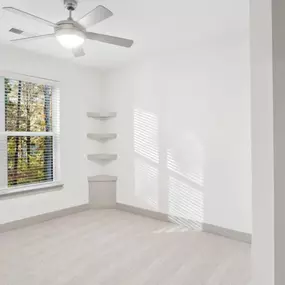 A room with a ceiling fan and a window with blinds.