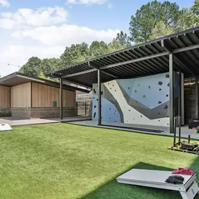 A climbing wall is in the middle of a grassy area.