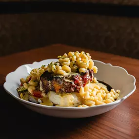 Beef and bacon meatloaf stuffed with cheddar cheese on top of mashed potatoes, topped with mac-n-cheese
