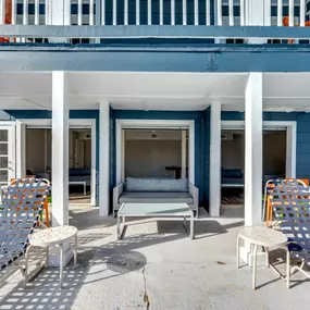 A white patio with a blue house in the background.