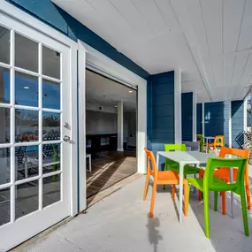 A white door opens to a patio with a table and chairs.