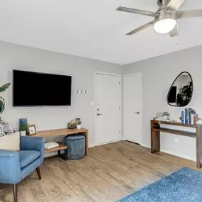A living room with a blue chair and a flat screen TV mounted on the wall.