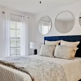 A bedroom with a bed and two mirrors above it