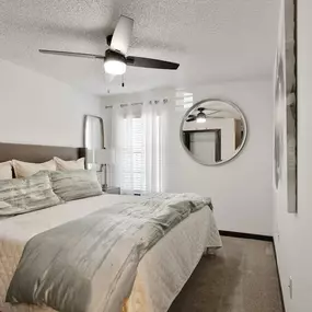 A bedroom with a bed and a ceiling fan
