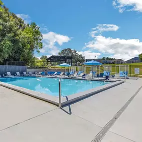 A resort style swimming pool with blue chairs around it
