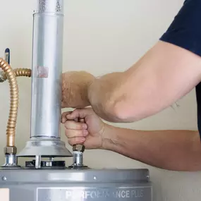 A professional plumber tightens fittings on a residential gas water heater, ensuring a secure, leak-free installation.