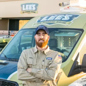 A technician labeled “Cotton” poses confidently in front of a Lee’s ac service van outside the company facility.