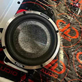 A close-up view of a car audio speaker, branded 
