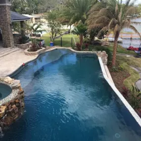Swimming pool in front yard with trees, grasses and plants beside