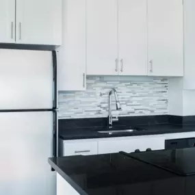 A modern kitchen with a black countertop and white cabinets