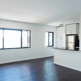 Spacious living room area with dark plank flooring and a large windows