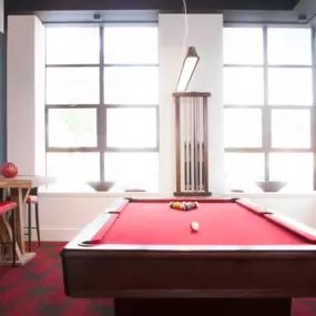 Resident game area with a pool table and high top tables with oversized windows