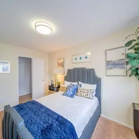 A bedroom with a bed and a potted plant