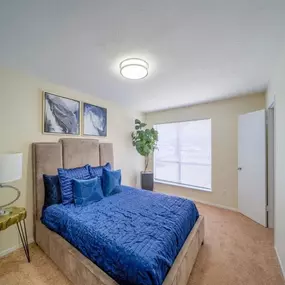 A bedroom with a large blue bed and a window