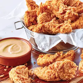 Crispy chicken tenders served in a bucket with bold spices and dipping sauce—perfect for game day, lunch breaks, or anytime cravings hit.