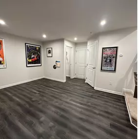Check out this stunning basement remodel featuring dark luxury vinyl plank flooring, fresh white walls, and recessed lighting. RO Contracting transformed this underused space into a modern, finished room—ideal for entertaining, relaxing, or a home office upgrade. The bold flooring contrasts perfectly with the clean aesthetic, delivering both durability and style.