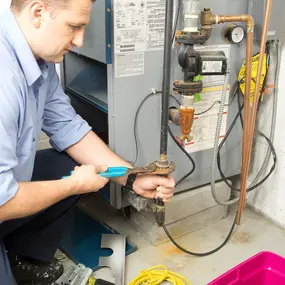 An HVAC technician is carefully inspecting and servicing a residential furnace, ensuring safe and efficient operation before the cold weather sets in. Equipped with tools and safety gear, the technician checks burners, wiring, and airflow components to diagnose issues or perform routine maintenance. This image highlights the importance of professional furnace service, heating system tune-ups, and seasonal HVAC maintenance to keep homes warm and energy-efficient during the winter months.