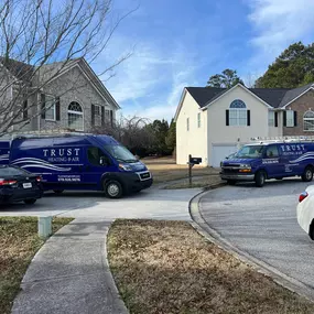 A quiet residential neighborhood features multiple Trust Heating and Air service vans parked in driveways and along the street, as technicians provide heating, cooling, and refrigeration services to local homes. The branded vehicles reinforce Trust's strong community presence, fast response times, and reputation for reliable HVAC service. This image highlights Trust Heating and Air as a go-to provider for homeowners in Northeast Georgia, delivering expert repairs, installations, and maintenance.