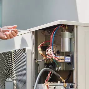 An HVAC technician is servicing an outdoor air conditioning unit, using diagnostic tools to inspect components, check refrigerant levels, and ensure the system is operating at peak efficiency. Dressed in uniform and focused on the task, the technician demonstrates the importance of professional A/C maintenance, timely repairs, and expert service to keep homes and businesses cool during hot weather.
