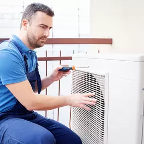 An HVAC technician is actively working on a central air conditioning unit, performing diagnostic tests and checking for issues to ensure proper cooling. Wearing a uniform and using professional tools, the tech demonstrates the importance of expert A/C repair, system maintenance, and seasonal tune-ups. This image captures the hands-on service that keeps residential and commercial HVAC systems running efficiently, especially during peak summer heat.