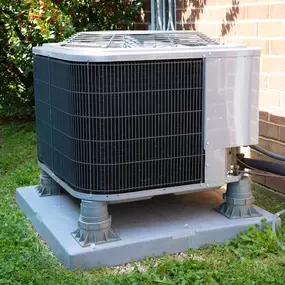 A residential outdoor air conditioning unit sits on a concrete pad beside a home, designed to provide reliable cooling during hot weather. The condenser is clean and professionally installed, with visible coils, fan, and protective casing. This image represents efficient home cooling, proper HVAC installation, and the importance of regular maintenance to extend system life and ensure energy-efficient performance. Perfect for promoting A/C service, repair, or system replacement.