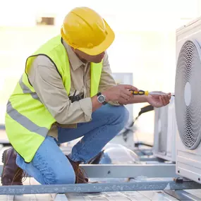An HVAC technician is servicing a large commercial air conditioning unit, performing diagnostics and maintenance on the rooftop or exterior of a business facility. Equipped with tools and safety gear, the technician ensures the system runs efficiently to maintain cooling for offices, retail spaces, or restaurants. This image represents professional commercial HVAC service, A/C system repair, and preventive maintenance to minimize downtime and improve energy performance.
