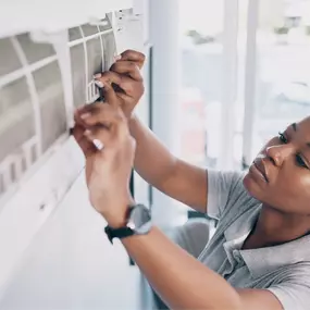 An HVAC technician is servicing a wall-mounted mini-split air conditioning unit inside a residential or light commercial space. Using specialized tools, the technician checks electrical connections, cleans filters, and ensures the system is operating efficiently. This image highlights the importance of professional mini-split A/C maintenance and repair, ideal for homes, offices, and spaces without traditional ductwork. It showcases energy-efficient cooling, zoned climate control, and expert HVAC