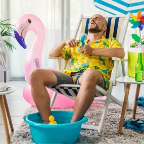 A comical scene of a man trying to beat the heat by sitting outdoors with his feet submerged in a tiny kiddie pool. Wearing sunglasses and fanning himself with a magazine, he’s clearly desperate to stay cool without air conditioning. This playful image humorously illustrates the struggle of summer heat and highlights the need for a reliable, professionally installed A/C system to avoid creative (and sweaty) cooling solutions.