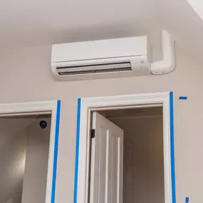 A wall-mounted mini-split air conditioning unit is installed inside a modern home, providing quiet, energy-efficient cooling without the need for ductwork. The sleek indoor unit blends seamlessly with the room's decor while delivering zoned climate control and personalized comfort. This image highlights the benefits of ductless A/C systems, ideal for home additions, older homes, or rooms that need targeted temperature control.