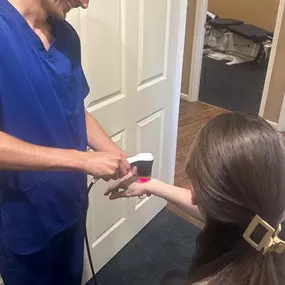 Dr. Gage Kirstein performing laser therapy on a patient's hand