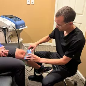 Dr. Gage Kirstein performing shockwave therapy on a patient's knee