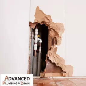 A severely damaged wall reveals exposed plumbing, illustrating a plumbing emergency or repair situation handled by Advanced Plumbing & Drain.