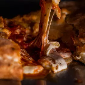 Close-up shot of a hot, cheesy slice of pizza from Southern Shores Pizza, showcasing the fresh ingredients and crispy crust.