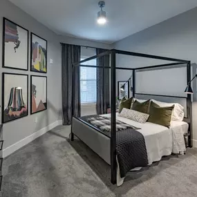 A bedroom with a bed and a dresser and a window