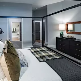 A bedroom with a bed and a dresser and a mirror