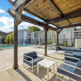 A covered patio with chairs and tables next to a pool