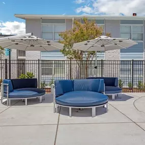 A patio with couches and umbrellas in front of a building