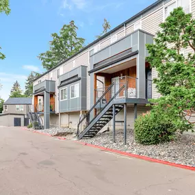 A modern two-story apartment with a grey exterior and a red border around the driveway.