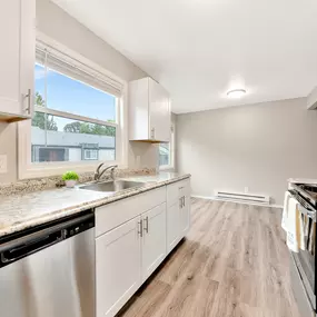 A kitchen with white cabinets and a marble countertop.