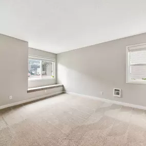 A room with a carpeted floor and a window with blinds.