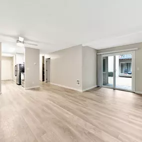 A spacious room with wooden flooring and white walls.