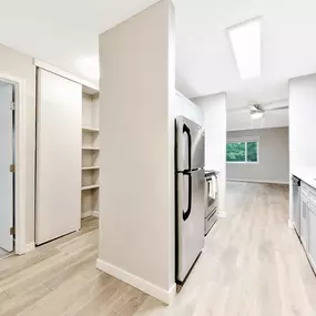 A kitchen with a refrigerator, sink, and cabinets.