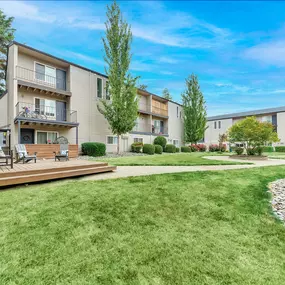 A sunny day at a well-kept apartment complex with a green lawn and trees.