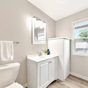 A white bathroom with a toilet, sink, and mirror.