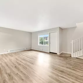 A spacious livingroom with wooden flooring and a staircase
